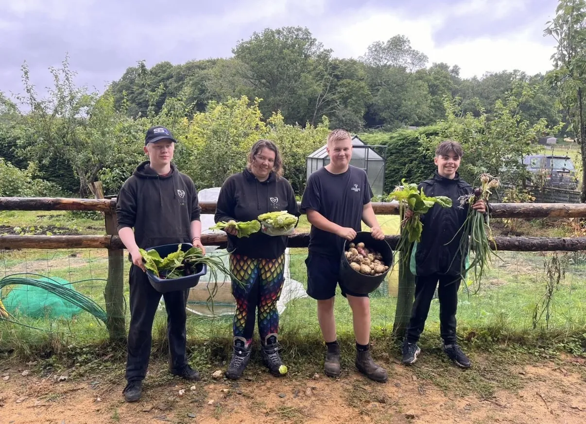 TEAL CIC learners holding harvested vegetables from the allotment