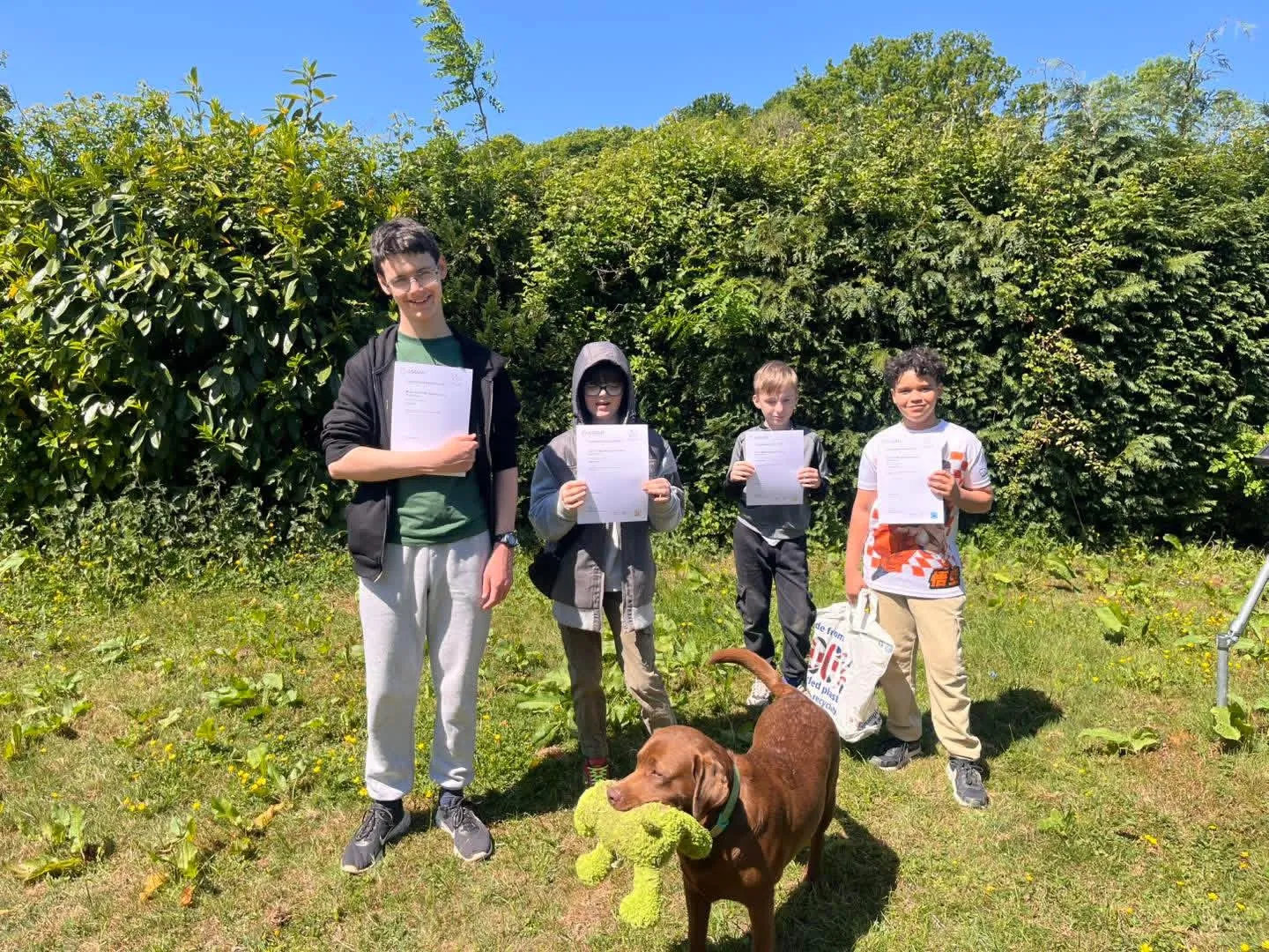 Young learners holding certificates outdoors at TEAL CIC